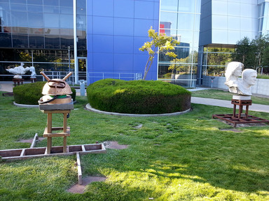 Statutes in park at the center of Google campus. Most of them are white statutes of significant people but one is not.